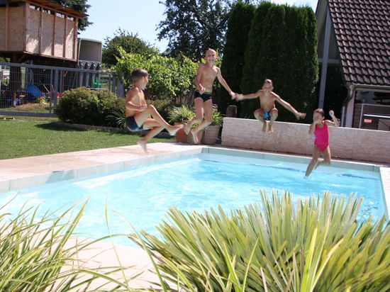 Vier Kinder springen in einen Pool.