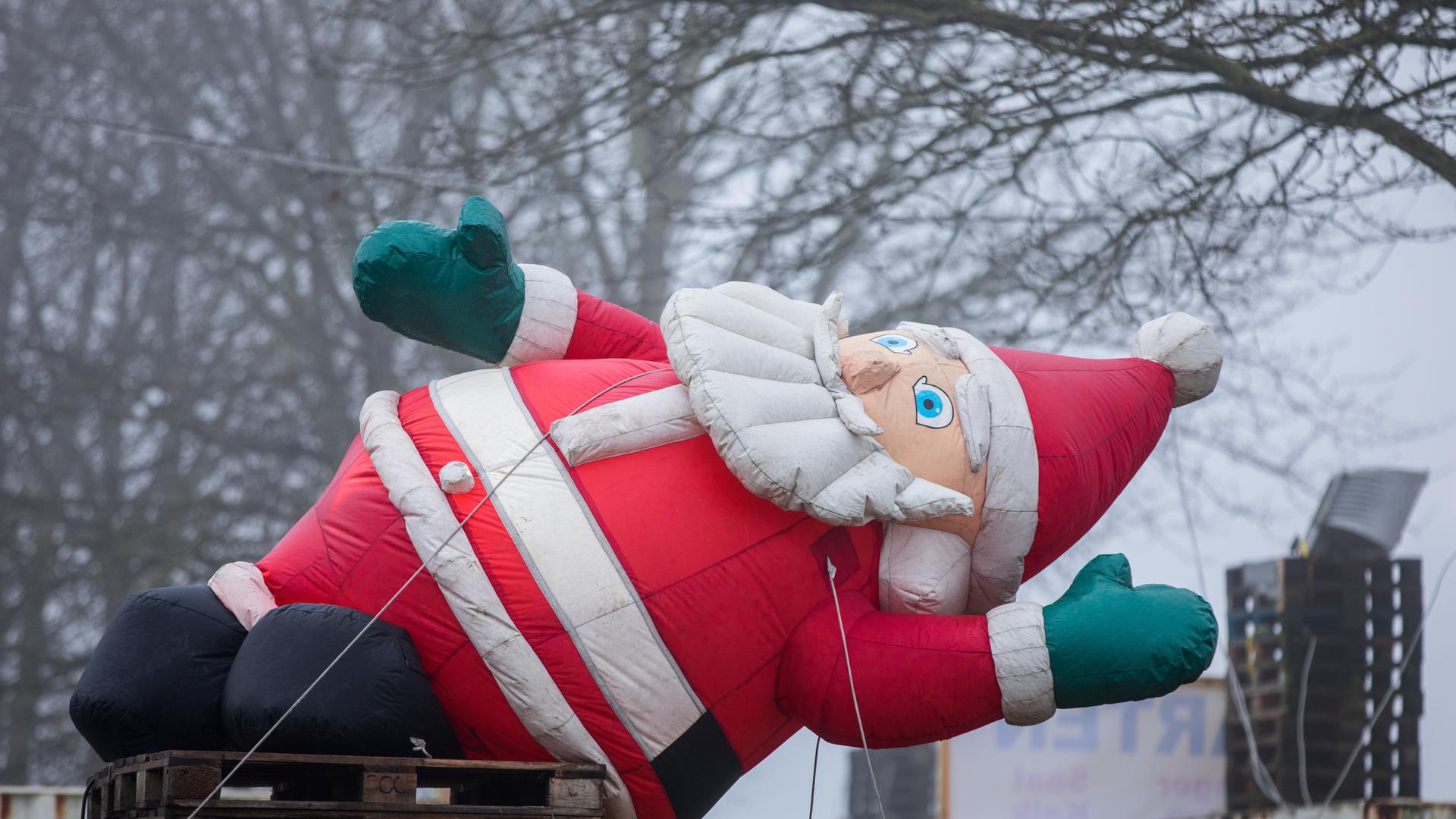 Ein aufblasbarer Weihnachtsmann liegt ) vor einem Einkaufsmarkt auf einem Palettenstapel. Mit Nebel und leichtem Niederschlag zeigt sich das Wetter in Norddeutschland kurz vor Weihnachten von seiner unfreundlichen Seite. Foto: Jens Büttner/dpa-Zentralbild/dpa +++(c) dpa - Bildfunk+++ | Verwendung weltweit