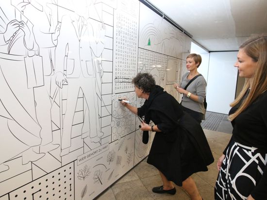 Drei Frauen stehen an einer Wandzeichnung.