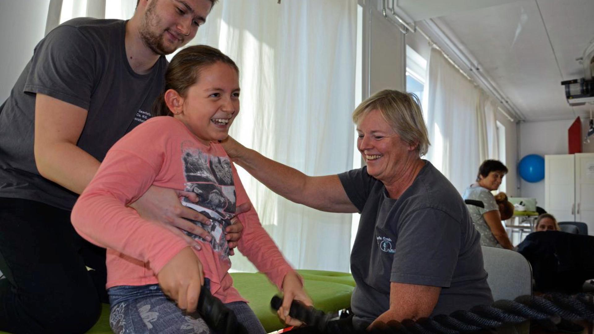 Mit Spaß und Eifer dabei: Die neunjährige Clara trainiert mit Helfer Bakir und Daniela Dorschner-Geerlofs an Seilen, um die Rumpfstabilität zu verbessern. Viele Wochen hat das Mädchen schon in der Pforzheimer Privatklinik verbracht mit dem großen Ziel, eines Tages wieder laufen zu lernen.