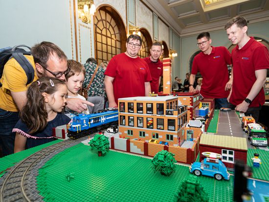 Ein Vater und seine zwei Kinder, fünf und sieben Jahre, aus Schömberg bewundern die Eisenbahnanlage bei den Legotagen. Im Hintergrund die Organisatoren aus Leipzig.         
