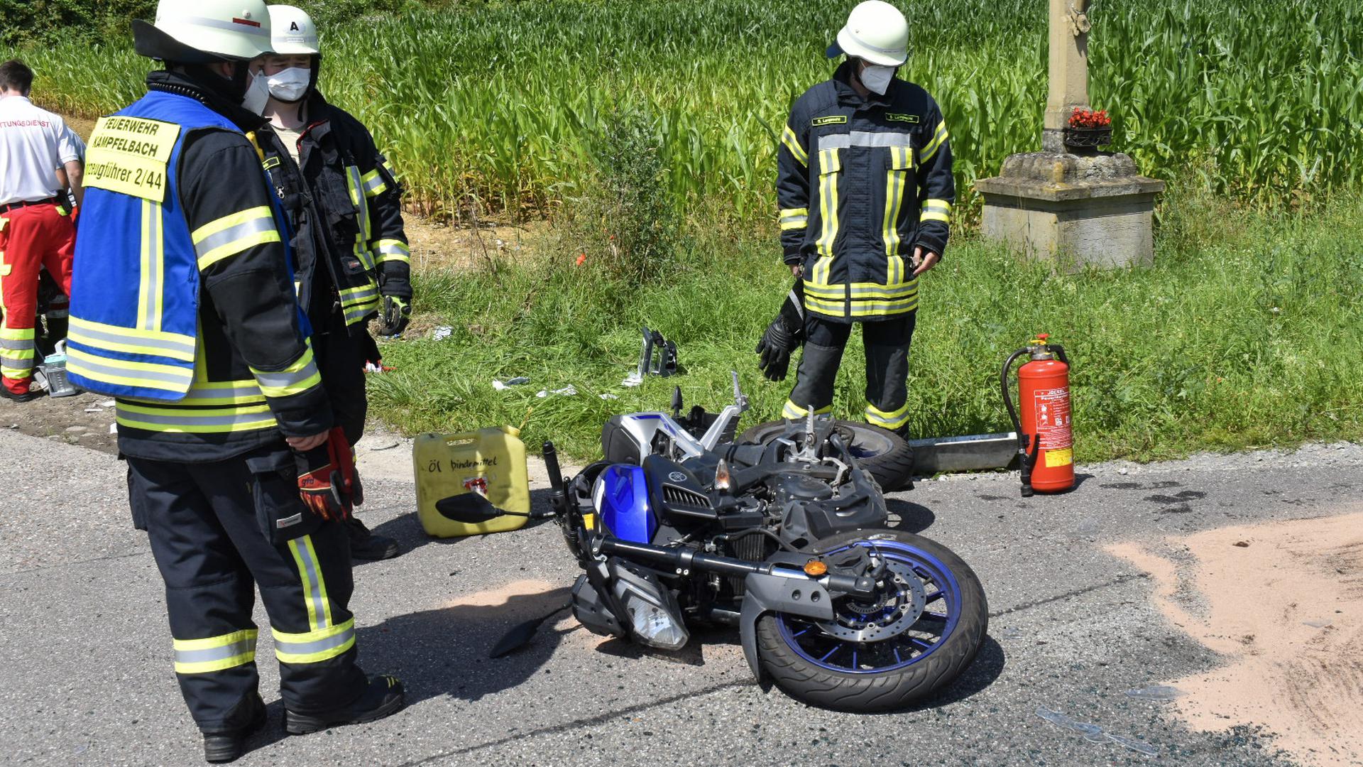 Einsatzkräfte der Feuerwehr Kämpfelbach stehen nach einem Unfall neben einem Motorrad, das auf der Straße liegt.