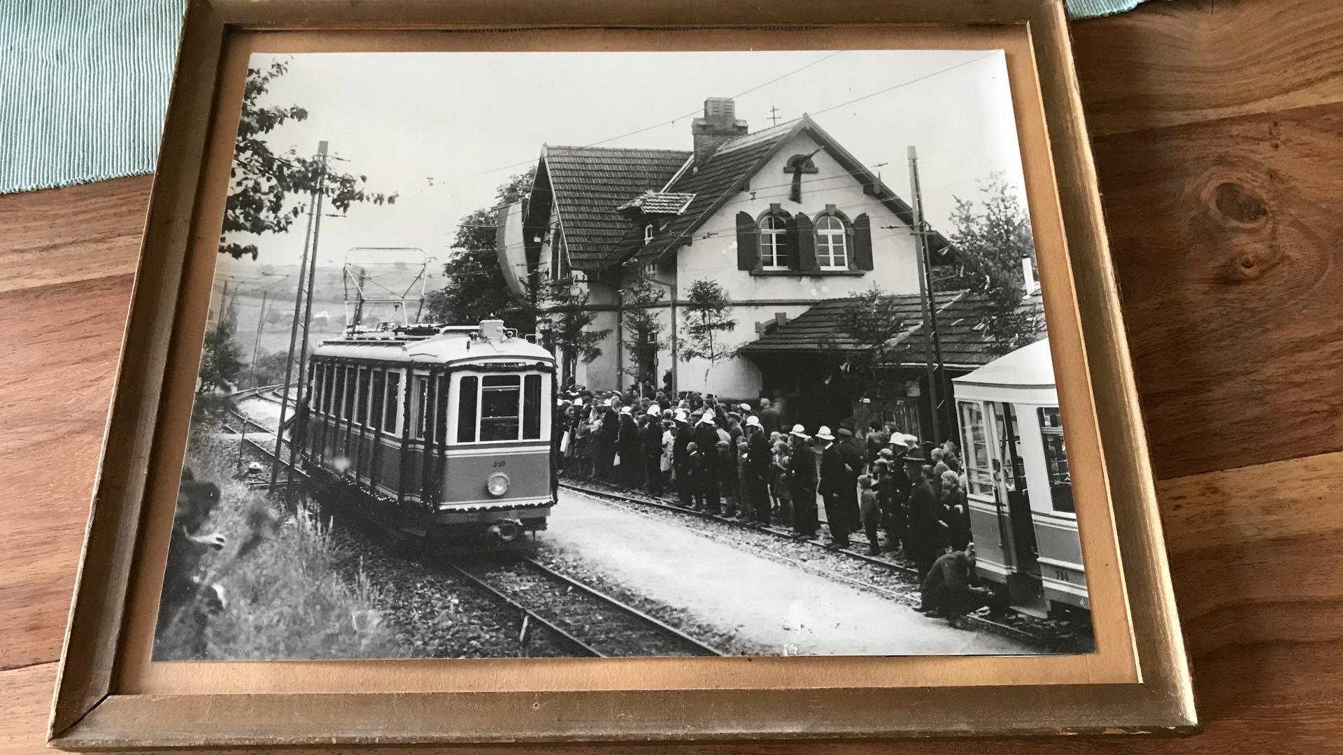 Ein gerahmtes Foto zeigt den alten Bahnhof in Ellmendingen voller Menschen, die am Gleis stehen. 