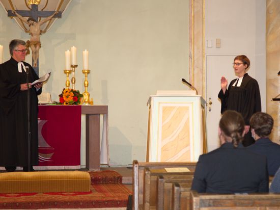 Investiturgottesdienst in der Stadtkirche Neuenbürg: Dekan Joachim Botzenhardt und die neue Arnbacher Pfarrerin Charlotte Moskaliuk stehen in Talare gekleidet vor einem Altar.
