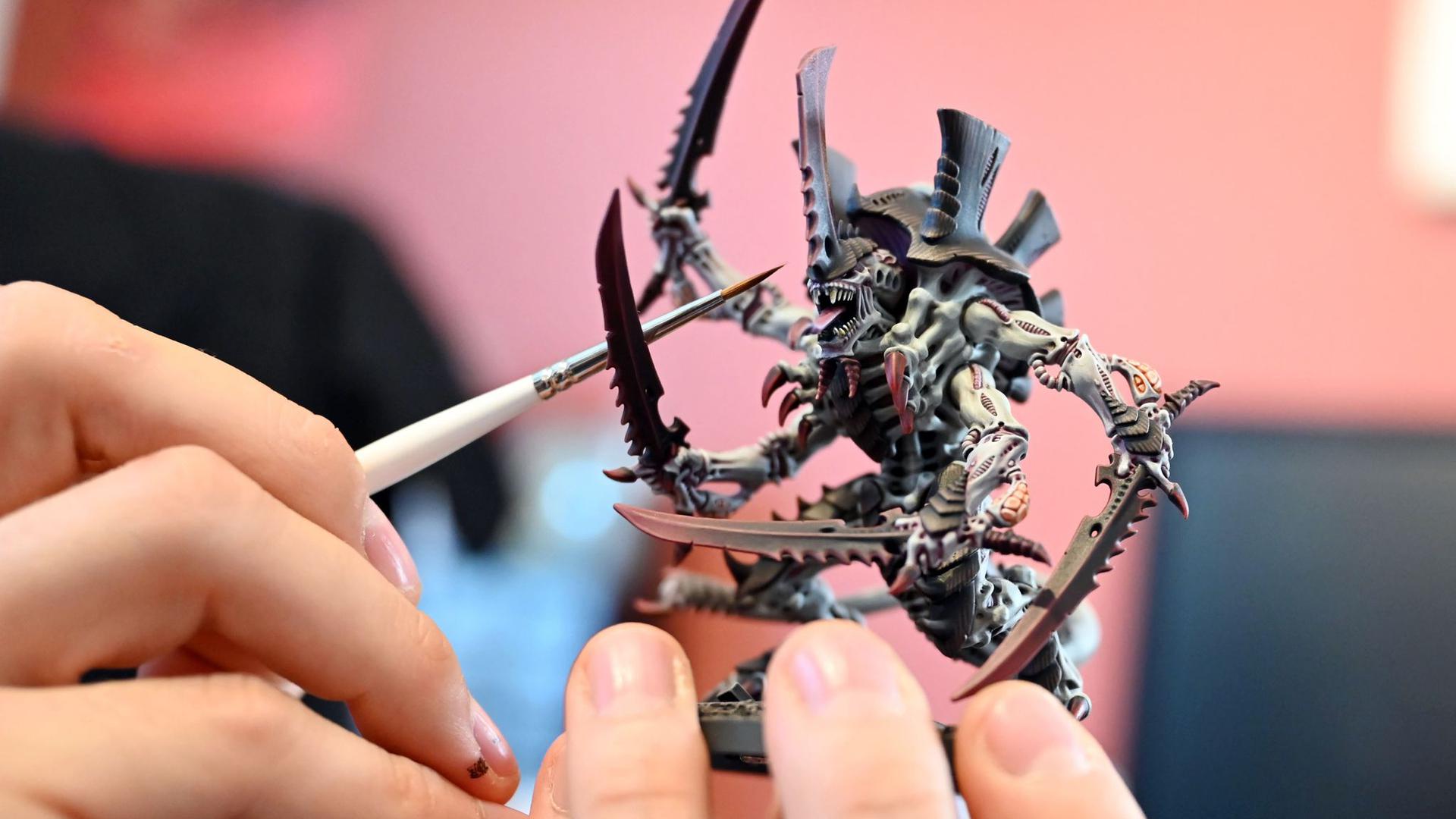 Den Kopfteil einer Warhammer-Spielfigur bepinselt Tim Winkler mit schwarzer Farbe. Details sind ihm wichtig.