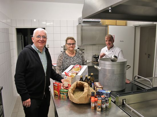 Drei Menschen stehen vor Lebensmitteln in einer Küche