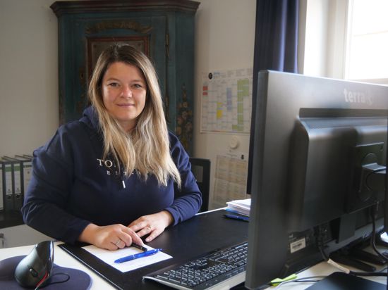 Frau im blauen Kapuzenpullover an Schreibtisch mit Rechner