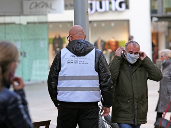 Freundliche Ermahnung: Ein Mitarbeiter der Pforzheimer „City-Streife“ erinnert an die neue Maskenpflicht in der Fußgängerzone.