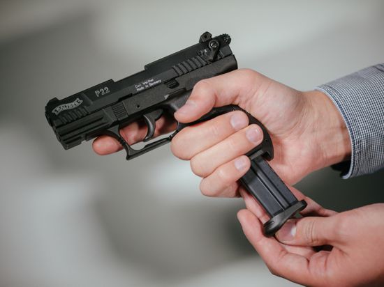 Hände laden eine Schreckschuss-Pistole «Walther P22» mit einem Magazin. 