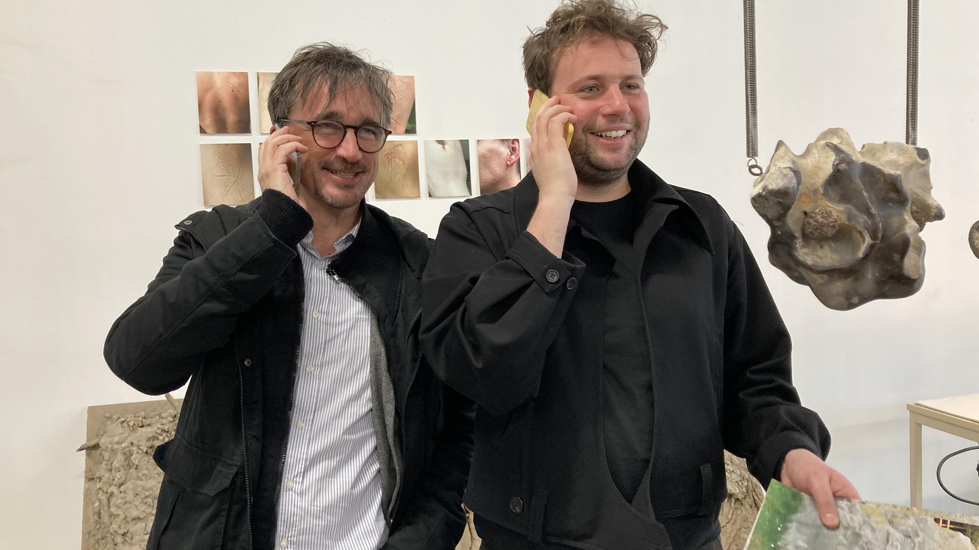 Christian Saalfrank und Jules van den Langenberg (von links) haben Spaß mit Stein-Handys von Wiktoria Wojciechowska , in deren Atelier in Paris