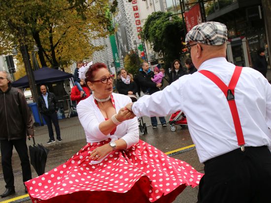 Ein Mann und eine Frau im Petticoat tanzen auf einer Straße.