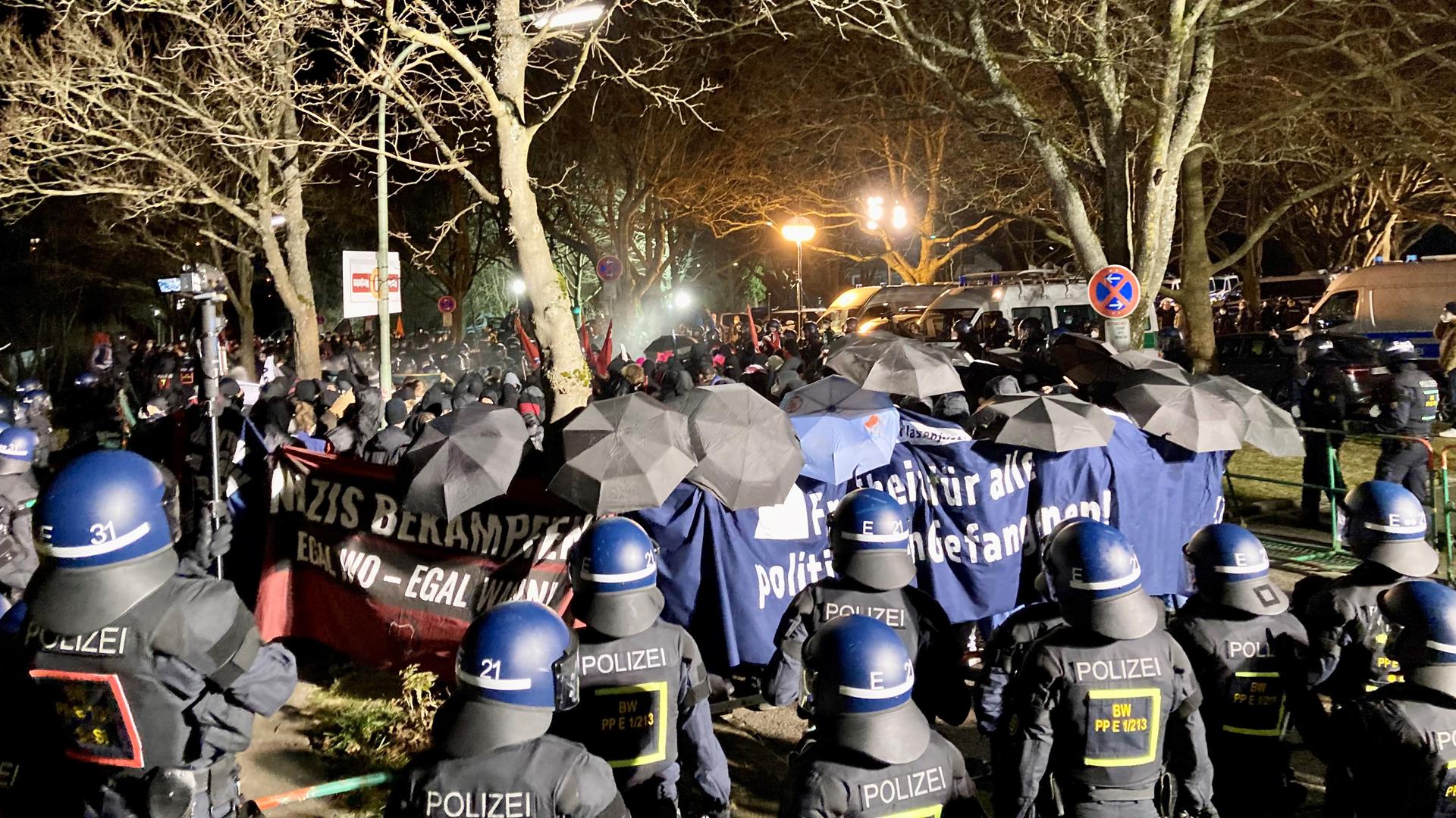 Mitglieder der Antifa verschanzen sich bei einer Demo am 23. Februar 2022 auf dem Pforzheimer Wartberg hinter Bannern und Schirmen. Die Polizei hat sie zurückgedrängt.
