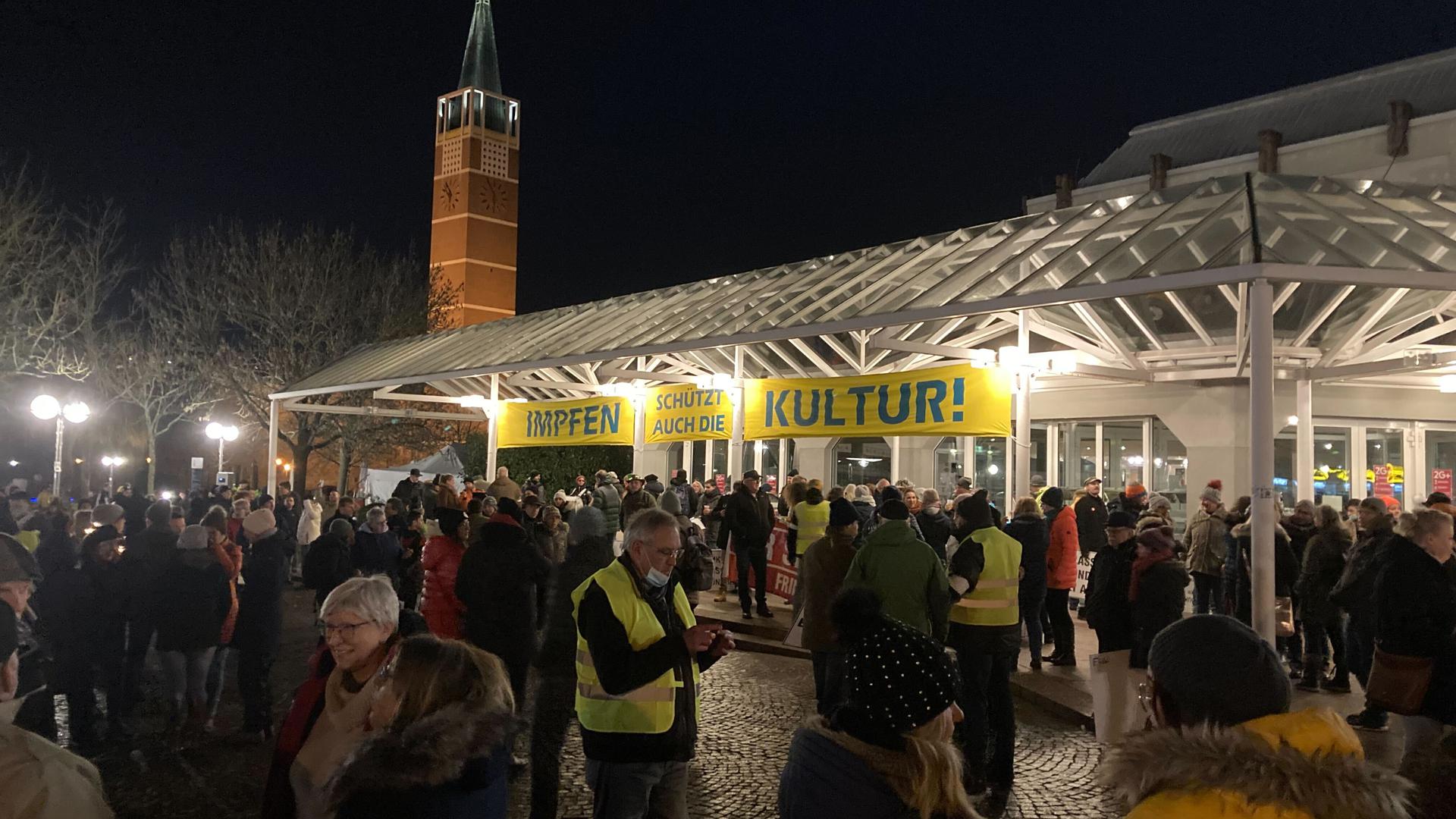 Die Teilnehmer der Corona-Demonstration in Pforzheim unter dem Schild „Impfen schützt auch die Kultur“ des Stadttheaters.
