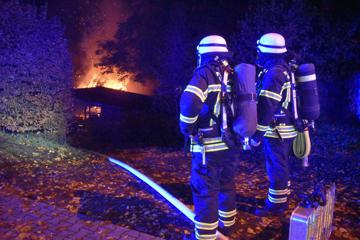 Zwei Feuerwehr-Einsatzkräfte beobachten den Brand einer Scheune in der Blumenthalstraße in Pforzheim.