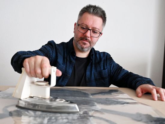 Oliver Lemke fertigt in seiner Wohnung eine Bügelperlenarbeit in Form eines Totenkopfs an.
