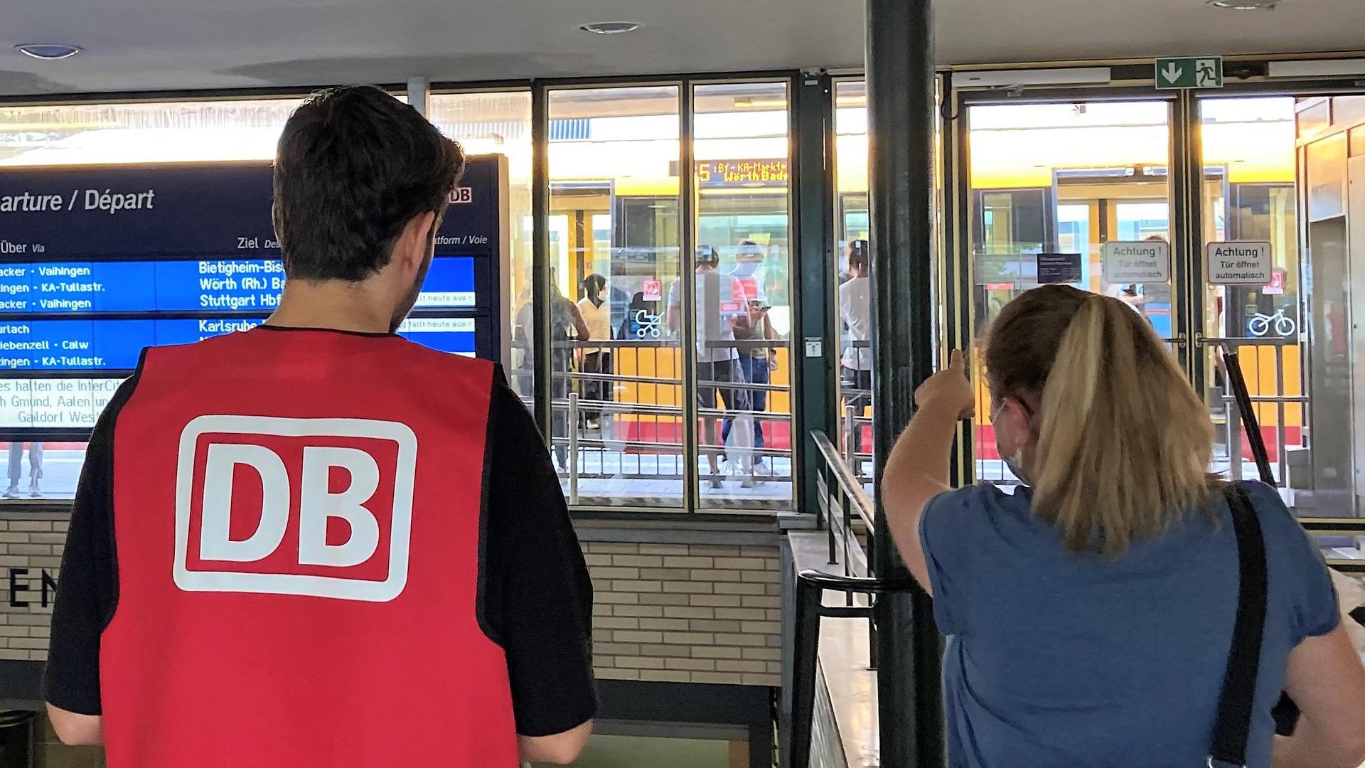 Ein Helfer der Deutschen Bahn beantwortet Fragen von Fahrgästen.