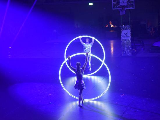 Eine Akrobatin und ein Akrobat mit LED-beleuchteten Cyr Wheels. 