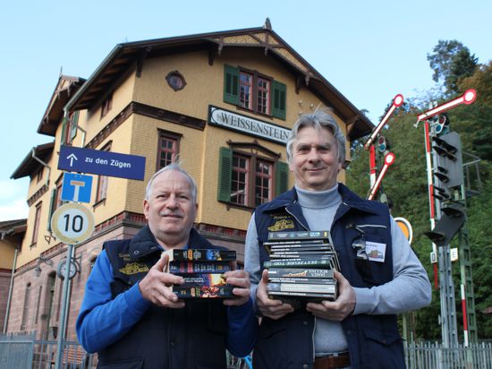Stellvertretender Vorsitzender der Eisenbahnfreunde, Rüdiger Baumann (links), und Schriftführer Andreas Richter stehen mit Büchern vor dem Weißensteiner Bahnhofsgebäude.