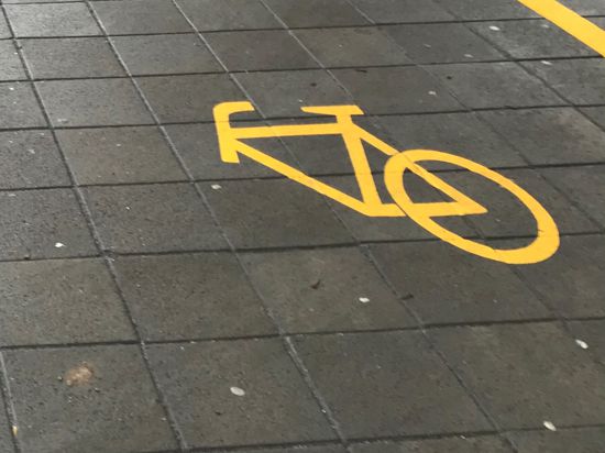 Ein Fahrradsymbol ist auf die Straße geklebt, dabei fehlt das Vorderrad.