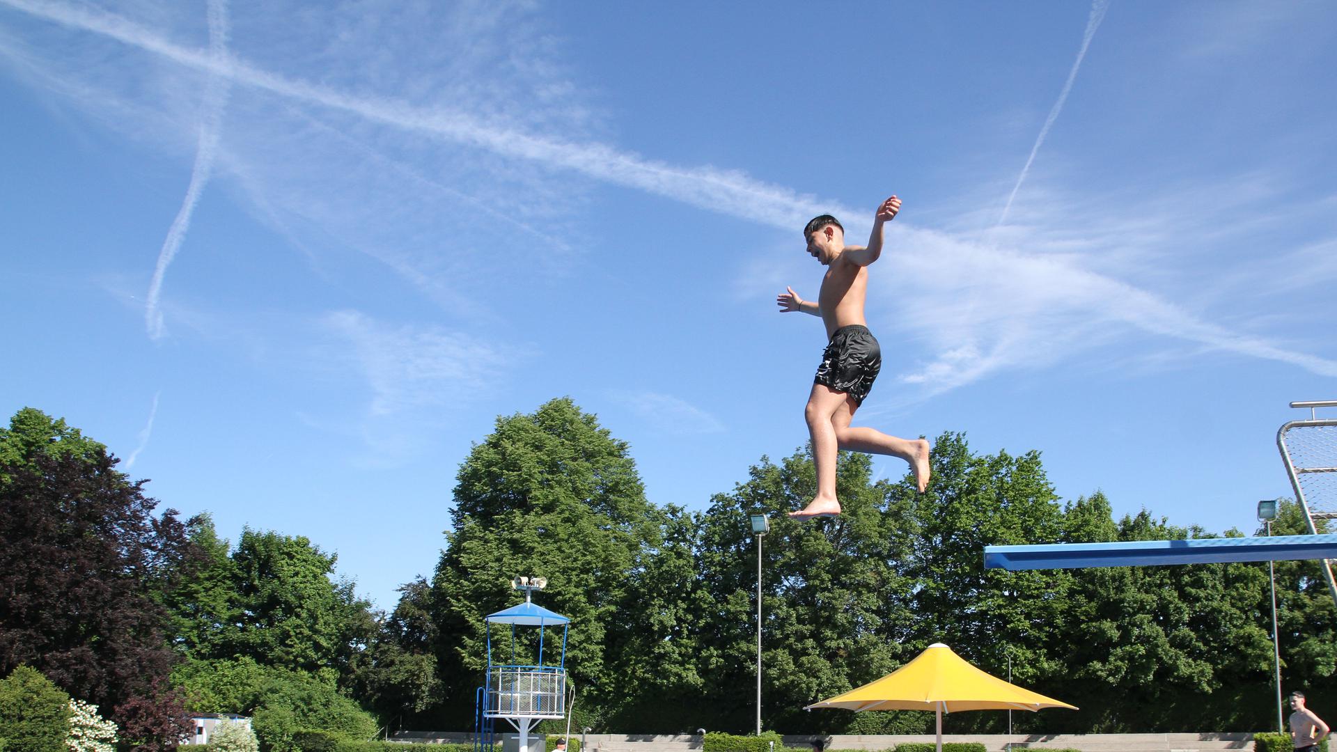 Ein Junge springt vom Drei-Meter-Brett ins Wasser