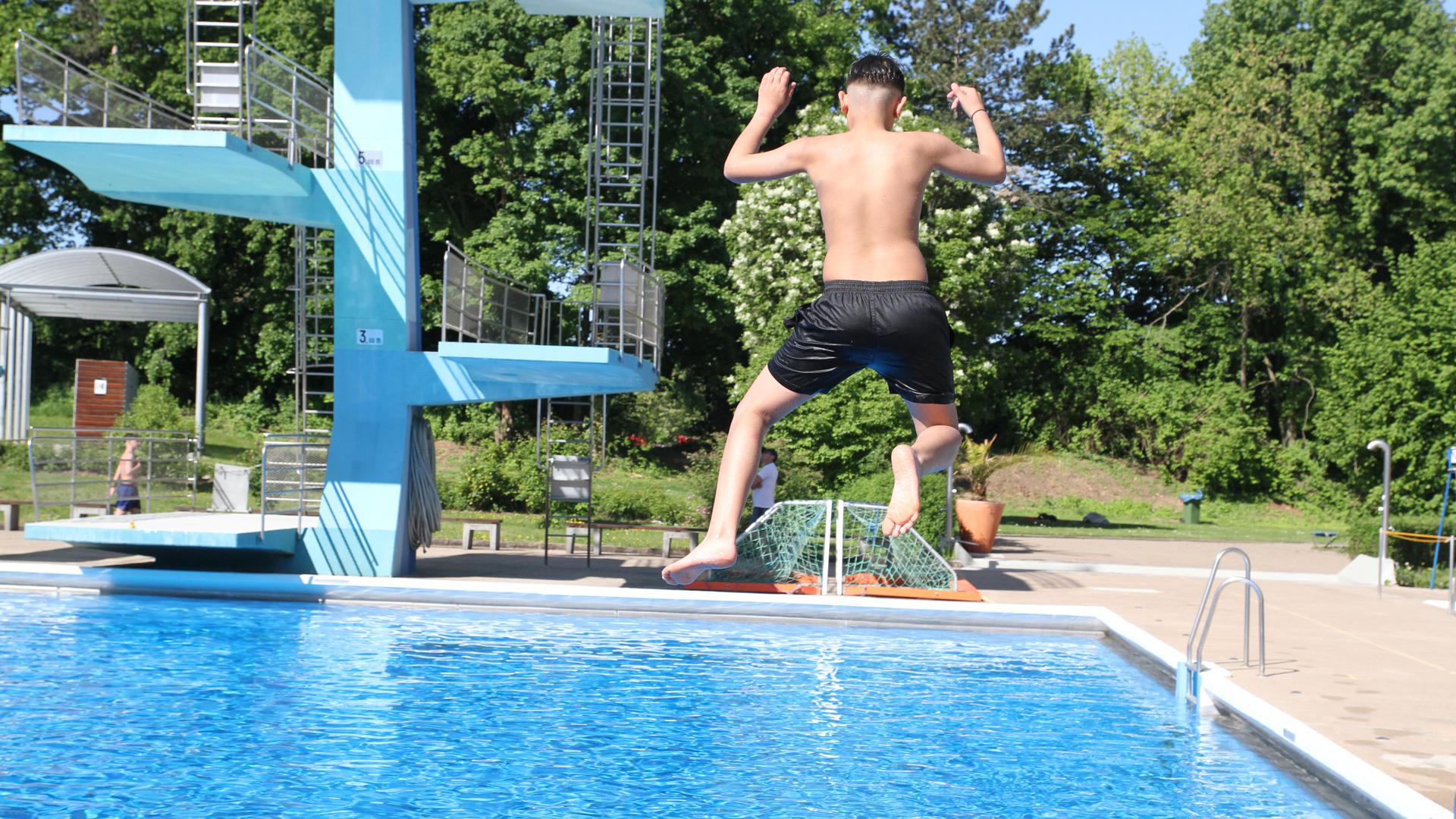 Ein Junge springt vom Sprungbrett ins Wasser