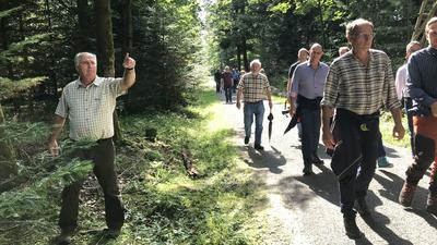 Mehrere Menschen laufen durch einen Wald, ein Mann zeigt mit dem Zeigefinger.