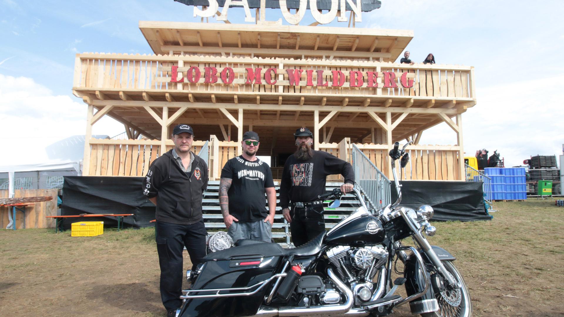 Drei Männer stehen vor einem selbst gebauten Saloon. Vor ihnen steht ein Motorrad. Es sind die Mitglieder des Lobo Motorcycle Clubs in Pforzheim, der vor 50 Jahren gegründet wurde. 