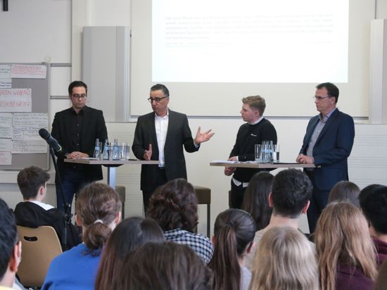 Vier Männer diskutieren vor Schülern im Hebel-Gymnasium.
