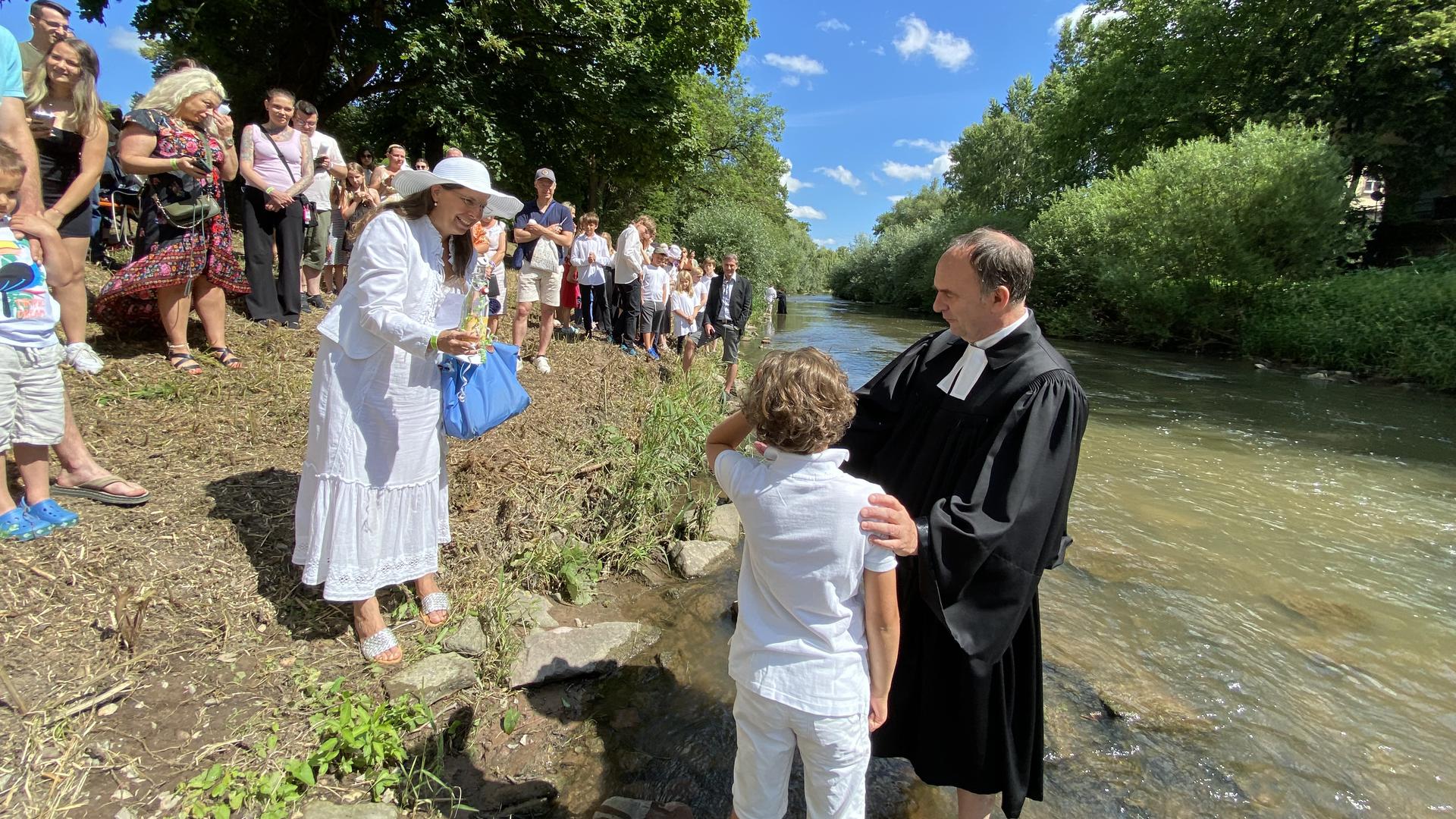 Taufe in der Nagold: Pfarrer Andreas Quincke segnete Maximilian Lang mit Flusswasser und mit Wasser aus dem Jordan, das Claudia Lang (links) bereithält.
