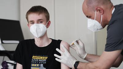 Jan Wolters (15) wird in einer Arztpraxis von dem Hausarzt Tim Koop (r) mit dem Serum von Biontech/Pfizer zu verabreichen. Die Ständige Impfkommission empfiehlt dies aber nur, wenn Vorerkrankungen vorliegen.