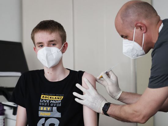 Jan Wolters (15) wird in einer Arztpraxis von dem Hausarzt Tim Koop (r) mit dem Serum von Biontech/Pfizer zu verabreichen. Die Ständige Impfkommission empfiehlt dies aber nur, wenn Vorerkrankungen vorliegen.