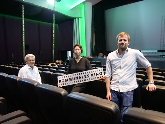 Drei Personen stehen in einem Kinosaal