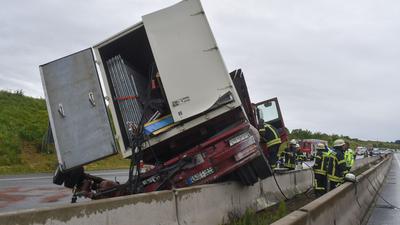 Ein Lastwagen steht nach einem Unfall auf der A8 bei Pforzheim mit einem Rad auf einer Betonschutzwand.