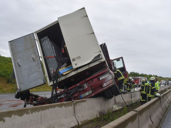 Ein Lastwagen steht nach einem Unfall auf der A8 bei Pforzheim mit einem Rad auf einer Betonschutzwand.