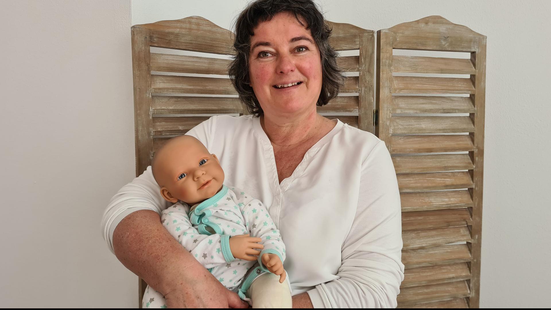Frau mit Puppe vor Paravent