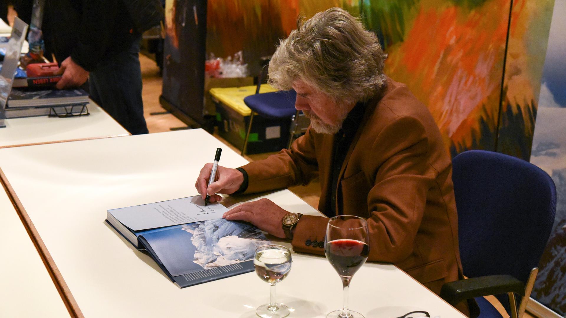 Ein Mann sitzt an einem Tisch und signiert ein Buch.