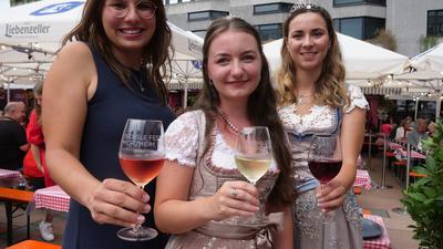 Drei junge Frauen halten Weingläser in Richtung Kamera