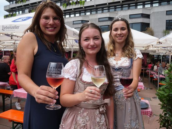 Drei junge Frauen halten Weingläser in Richtung Kamera