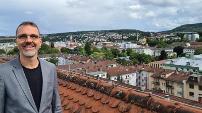 Ein Mann (Paul Taube, der Leiter des Kulturhauses Osterfeld) steht auf dem Dach des Kulturhauses Osterfeld und genießt den Blick auf Pforzheim. 