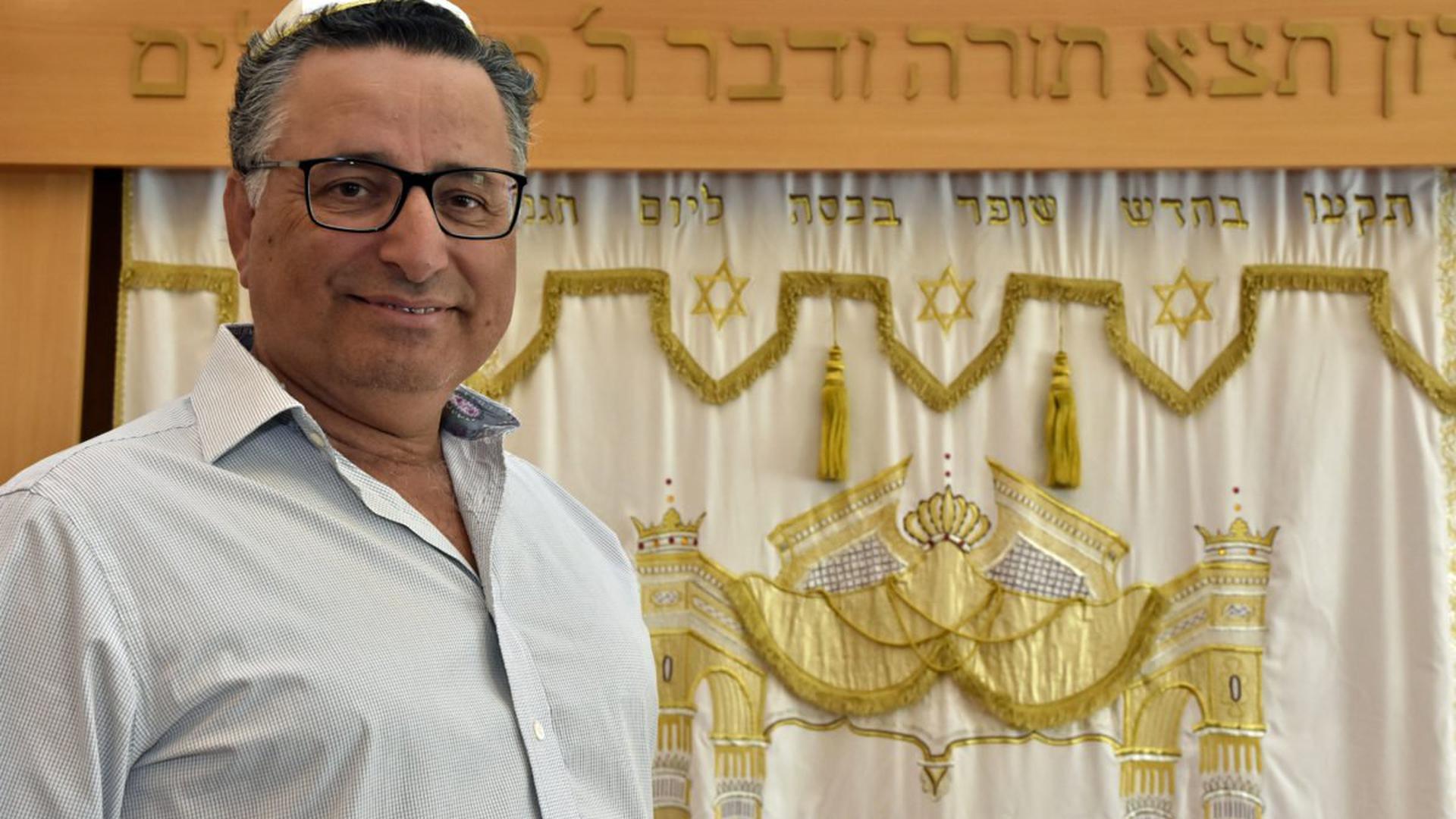 Rami Suliman vor einem Vorhang mit hebräischer Schrift und Davidssternen darauf.