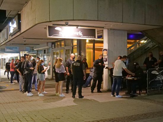 Vor einem Tisch, an dem die Personalien der Besucher aufgenommen werden, stehen mehrere Personen Schlange, um in den Nachtclub eingelassen zu werden.