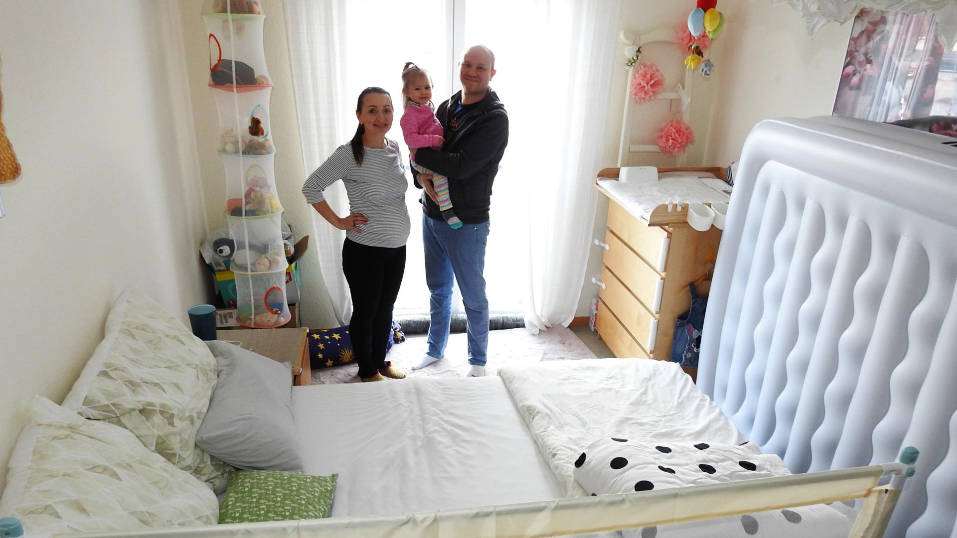 Familie Diana und Marco Simon mit Tochter in ihrem Schlafzimmer.