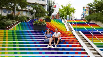 Linda Wendel und Bart Dewijze - das Künstlerduo The Artpole - auf der Treppe am Blumenhof, die durch ein Mitmachprojekt des Künstlerduos Farbe bekam.