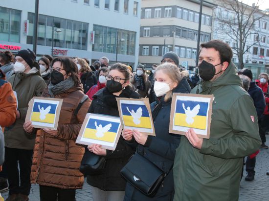 Demonstranten halten bei einer Friedenskundgebung für die Ukraine auf dem Pforzheimer Leopoldplatz ukrainische Flaggen mit Friedenssymbolen in Händen.