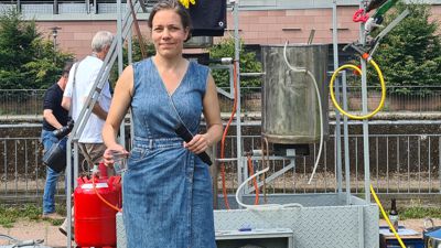 Eine junge Frau (Künstlerin und Designerin Henriette Waal) steht vor einer mobilen Brauerei.
