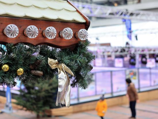 Ein geschmückte Weihnachtsmarktbude, dahinter die Eislaufbahn vor dem Pforzheimer rathaus