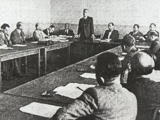 Mehrere Männer sitzen um einen Tisch, schwarz-weiß-Aufnahme
