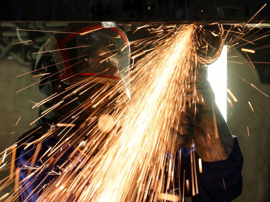 Ein Mitarbeiter eines Maschinenbauers schneidet mit einem Trennschleifer korrodierte Metallteile aus dem Träger in einem Wagenkasten.
