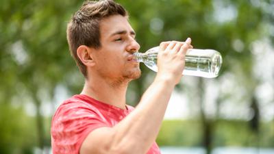 ILLUSTRATION - Ein junger Mann trinkt am 15.07.2019 in einem Park in Muenchen aus einer Wasserflasche (gestellte Szene). Foto: Tobias Hase || Modellfreigabe vorhanden