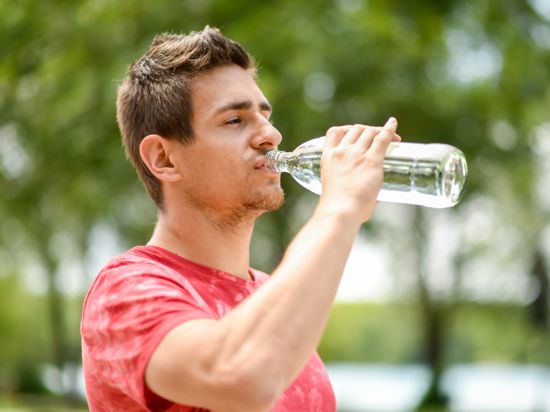 ILLUSTRATION - Ein junger Mann trinkt am 15.07.2019 in einem Park in Muenchen aus einer Wasserflasche (gestellte Szene). Foto: Tobias Hase || Modellfreigabe vorhanden